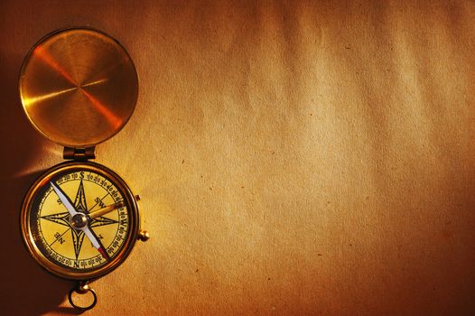 Antique brass compass over old paper background