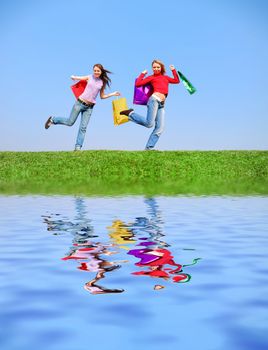 Girls with bags against blue sky with reflection on water