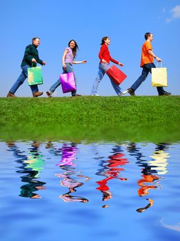 People with bags against blue sky with reflection on water