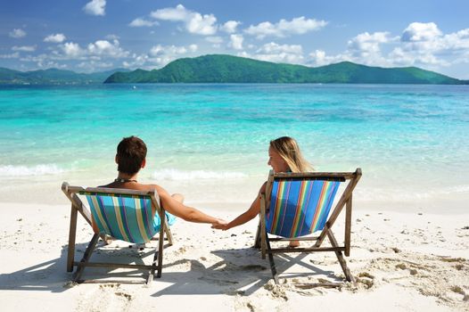 Couple on a tropical beach in chaise lounge