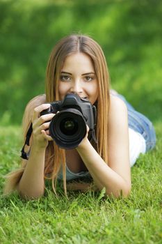 Young woman making photos at summer green park.
