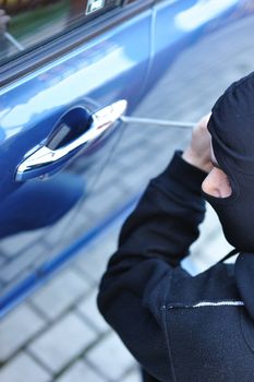 Young man in mask trying to steal a car