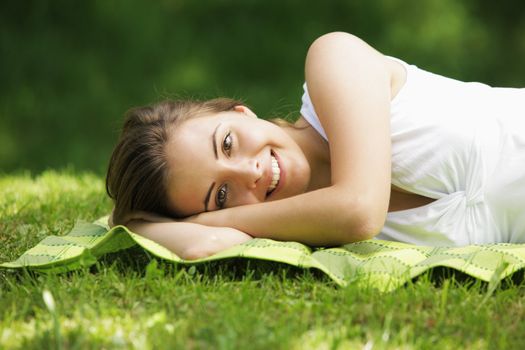 Young smiling woman laying on the grass 