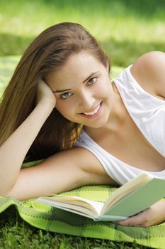 Closeup of a beautiful young woman reading book at park