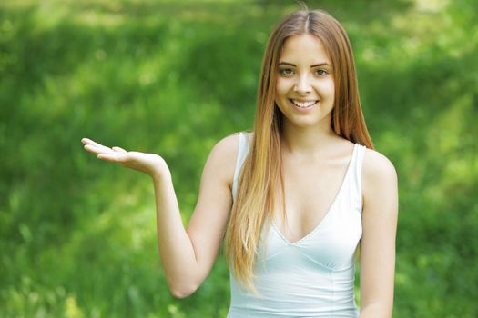 Smiling young woman pointing at copy space on green background