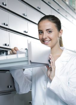 Beautiful young woman pharmacist reaching for medicine