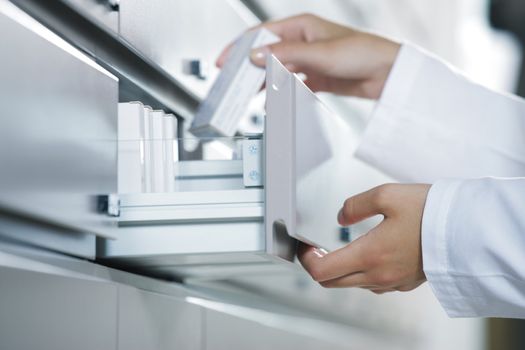 Close up view of pharmacist taking medicine from drawer