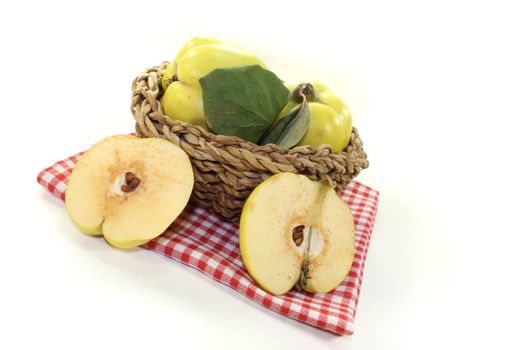 fresh Quinces with leaves in a basket on a bright background