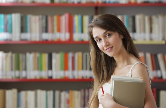 Portrait of a young smiling student in a library