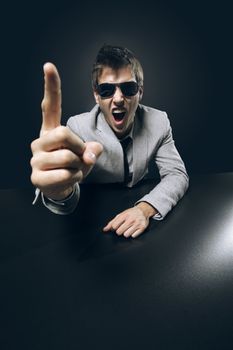 Young angry businessman boss is pointing his finger and screaming