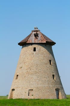 old windmill with stork nest on roof