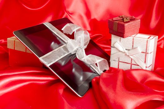 Digital tablet with christmas present on red background