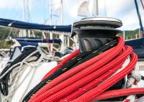 Winch detail with red and black rope in a sailboat