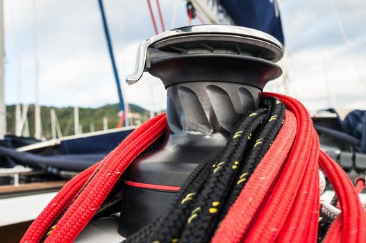 Winch detail with red and black rope in a sailboat