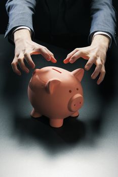 Hands reaching for a piggy bank