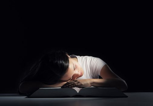 Student tired of studying, he falls asleep over the book
