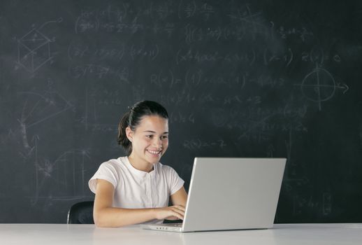Young girl with laptop, blackboard on background