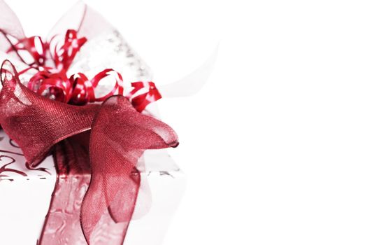 closeup of a silver christmas present with red ribbons on white background