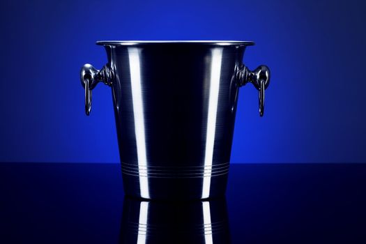 empty champagne bucket on a mirror with blue background