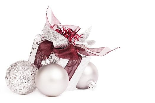 silver christmas present with red ribbons and christmas balls on white background
