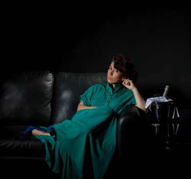 Beautiful girl sitting on a sofa, black background