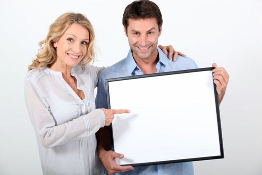 Couple pointing at blank board