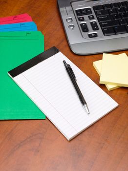 Close-up shot of a ballpoint pen with notepad and files on wooden office desk.