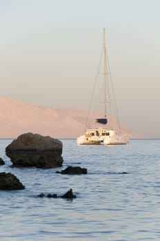 Nice catamaran yacht in beauty blue bay at sunset light