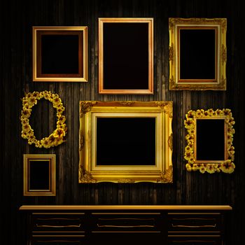 Gallery display - vintage gold frames and a chest of drawers on an old timber wall