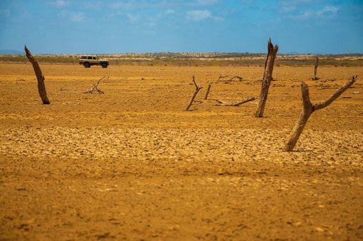 A view of a desolate desert with an SUV in the background.