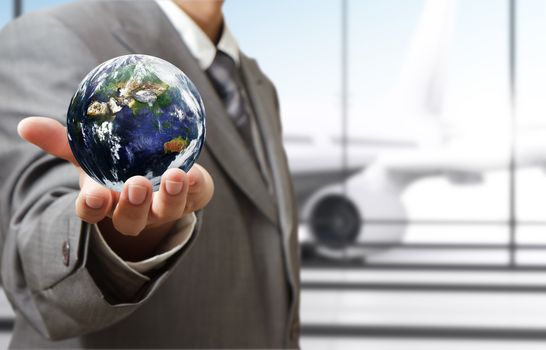 business man holds globe in the airport"Elements of this image furnished by NASA"