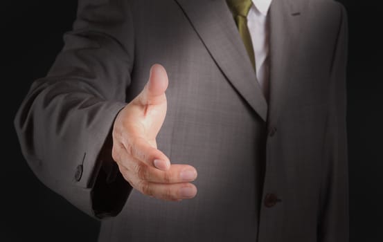 Businessman offering for handshake on dark background