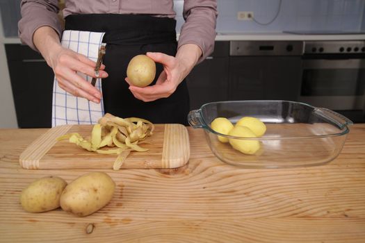 Peeling a potato with peeler in a kitchen