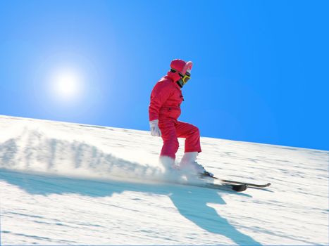 The young girl on skis goes from mountain in a spotty suit