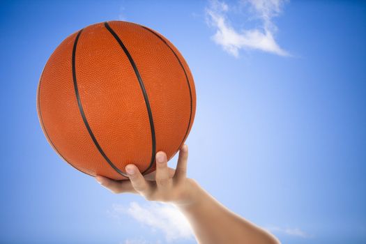 Image of basketball on the hand and sky as background