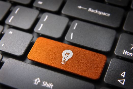 Internet business new ideas concept: orange key with bulb lamp icon on laptop keyboard. Included clipping path, so you can easily edit it.