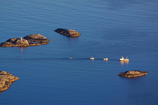 Bird eye view of fishing boats sailing between by rocky islets near Henningsvaer on Lofoten islands in Norway