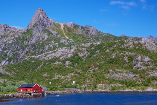Typical red fishing hut in fjord on Lofoten islands in Norway