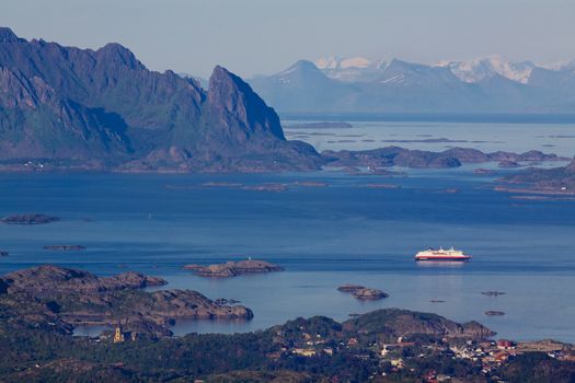 Large cruising ship leaving town of Svolvaer on Lofoten islands in norway with scenic panorama