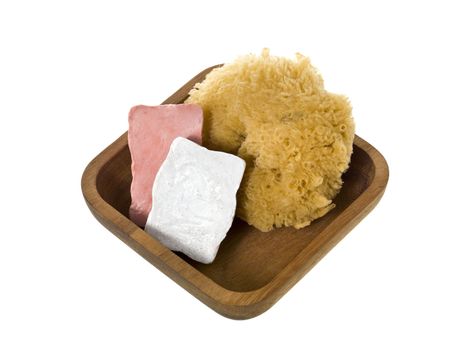 Close-up image of a wooden container with bar soap and loofah isolated on a white background