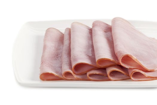 Close up image of slices of ham on white plate against white background