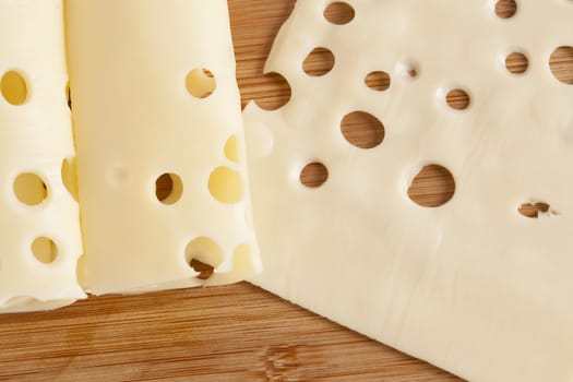 Thin slices of cheese over a wooden background