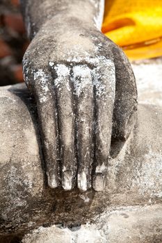 Stone hand of Buddha covered by orange fabric from the temple of Wat Yai Chai Mongkol in Ayutthaya, Thailand.