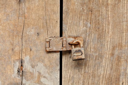 Old Wooden door locked with rusty padlock