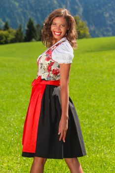 Young Brazilian woman in Bavarian dress on a mountain meadow
