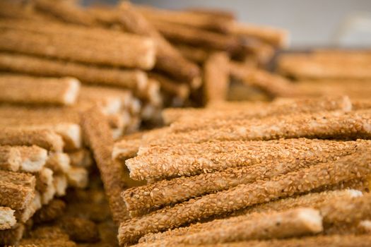 Close up photo of lots of sesame sticks in a pile in a counter of a shop