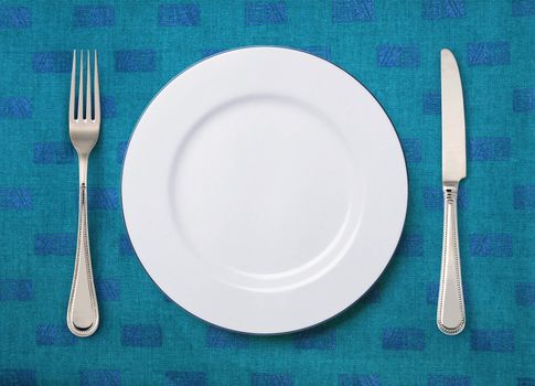 round white plate, knife and fork on table