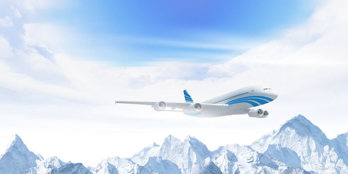 White passenger plane flying in the blue sky above the mountains with snow tops