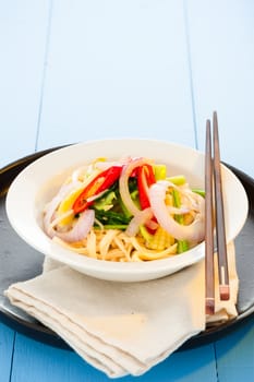 spicy vegetarian noodle in a white plate and light blue wooden table