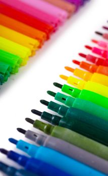Closeup view of a row of colorful felt tip pens over white background